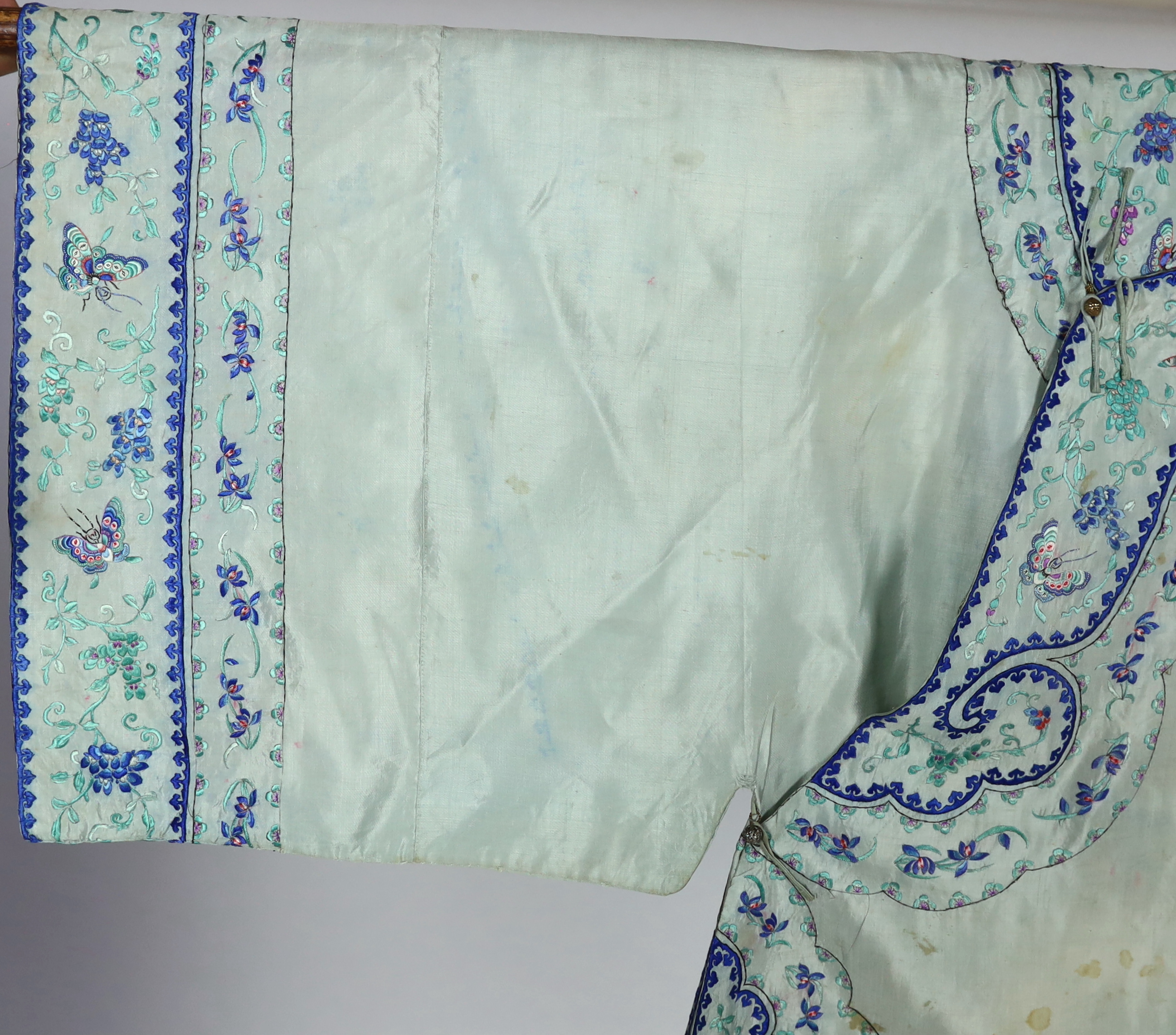 A 1930's Chinese silk embroidered robe, in pale turquoise silk with wide pastel embroidery of butterflies and flowers, 88cm long